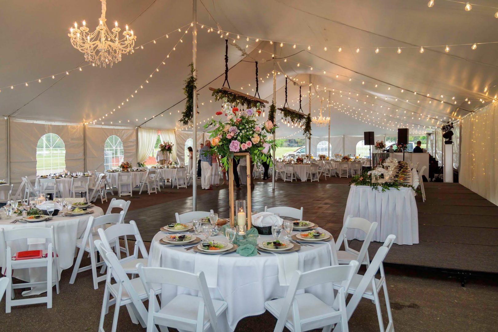 Tent with strings lights and chandeliers strung across the top.